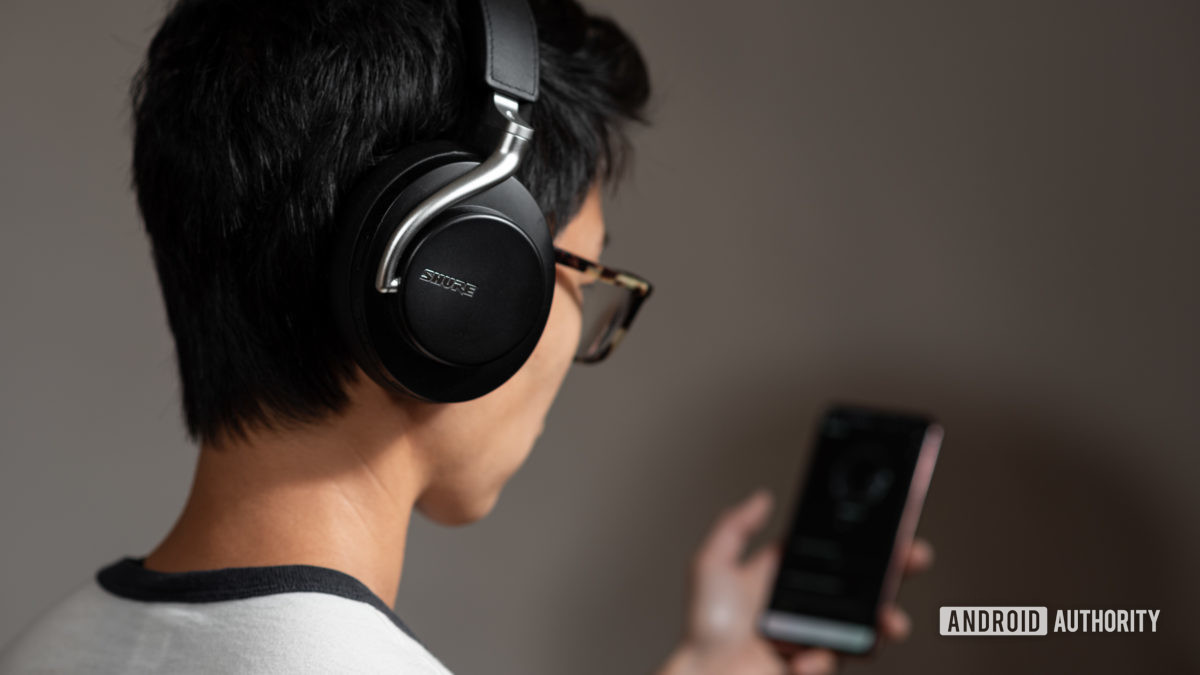 Los auriculares con cancelación de ruido Shure Aonic 50 usados por una mujer que utiliza la aplicación móvil de Shure.
