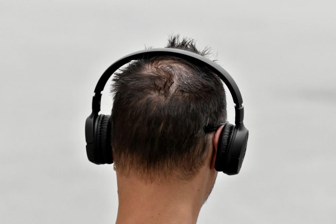 Vista trasera de un hombre con auriculares de botón (De: Pixnio)