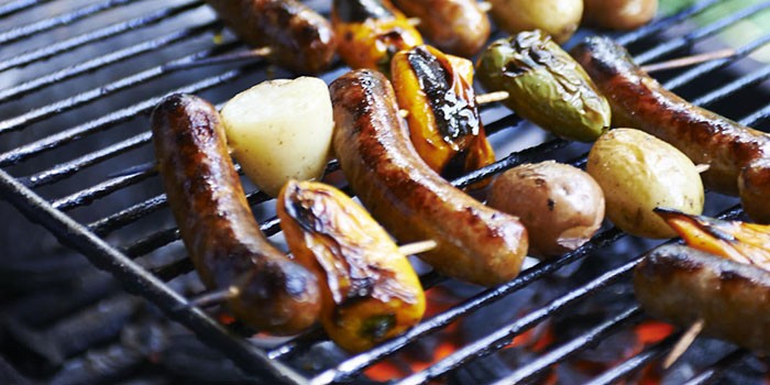 Salchichas cocinando en una barbacoa de carbón