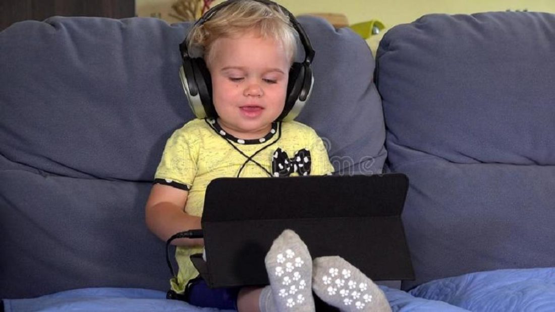 Niño pequeño viendo algo en el IPAD con auriculares (de dreamstime.com)